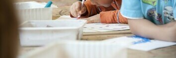 Boy colouring at table with other children